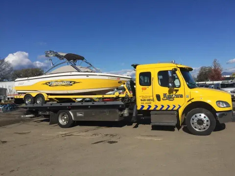 Keith's Towing truck towing a boat on a trailer