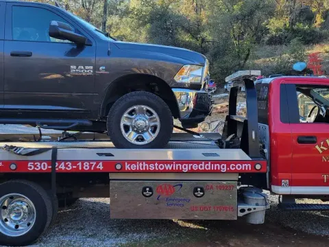 Keith's Towing flatbed truck loaded with a pickup truck